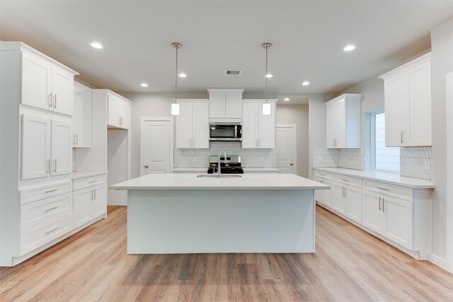 6615 Ezzard Charles Ln, Houston, TX 77091 - kitchen with stainless steel appliances, an island with sink, decorative backsplash, white cabinets, and recessed lighting