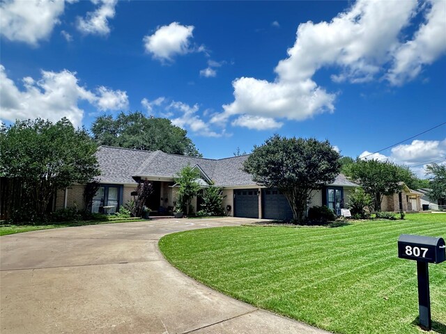 807 Trochta St, El Campo, TX 77437 - view of front facade featuring driveway, a front lawn, a garage, a shingled roof, and brick siding