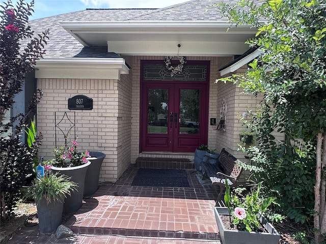 807 Trochta St, El Campo, TX 77437 - view of exterior entry with french doors, a shingled roof, and brick siding