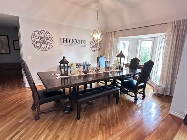 807 Trochta St, El Campo, TX 77437 - dining room featuring a chandelier, baseboards, light wood-style floors, and vaulted ceiling