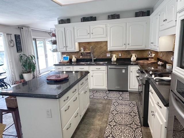 807 Trochta St, El Campo, TX 77437 - kitchen featuring stainless steel appliances, a sink, dark countertops, and white cabinets