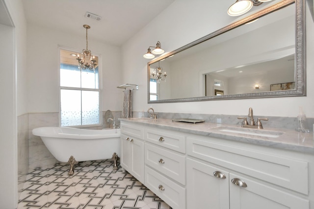 928 Dunbar St, Houston, TX 77009 - bathroom featuring a chandelier, double vanity, a soaking tub, tile walls, and wainscoting