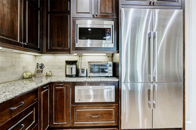 1418 Du Barry Ln, Houston, TX 77018 - kitchen with appliances with stainless steel finishes, a warming drawer, dark brown cabinets, light stone countertops, and backsplash