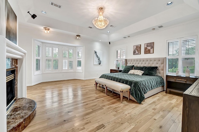 1 Magnolia Bend Dr, Hunters Creek Village, TX 77024 - bedroom featuring a tray ceiling, light wood-type flooring, a chandelier, a fireplace with raised hearth, and recessed lighting