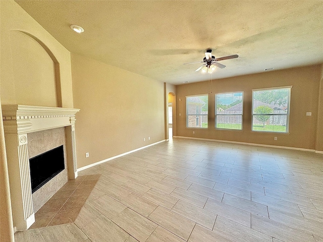 2115 Mooncrest Dr, Houston, TX 77089 - unfurnished living room featuring a ceiling fan, a tile fireplace, a textured ceiling, baseboards, and arched walkways