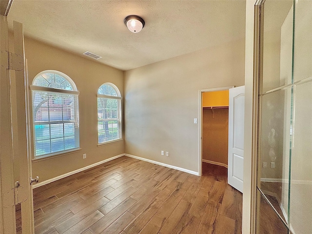 2115 Mooncrest Dr, Houston, TX 77089 - unfurnished bedroom featuring wood finished floors, a textured ceiling, baseboards, a closet, and a walk in closet