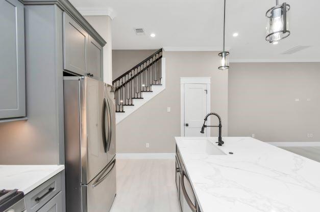 1708 Capron St Unit A, Houston, TX 77020 - kitchen with appliances with stainless steel finishes, gray cabinetry, light stone countertops, a sink, and light wood finished floors
