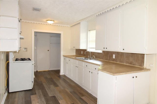 916 Cedar Bayou Rd, Baytown, TX 77520 - kitchen featuring gas range gas stove, a sink, tasteful backsplash, dark wood finished floors, and white cabinetry