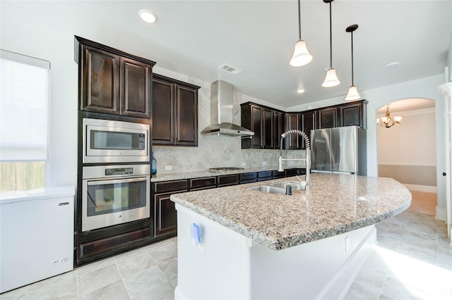 1103 River Delta Ln, Rosenberg, TX 77469 - kitchen with appliances with stainless steel finishes, wall chimney exhaust hood, a sink, decorative backsplash, and light stone counters