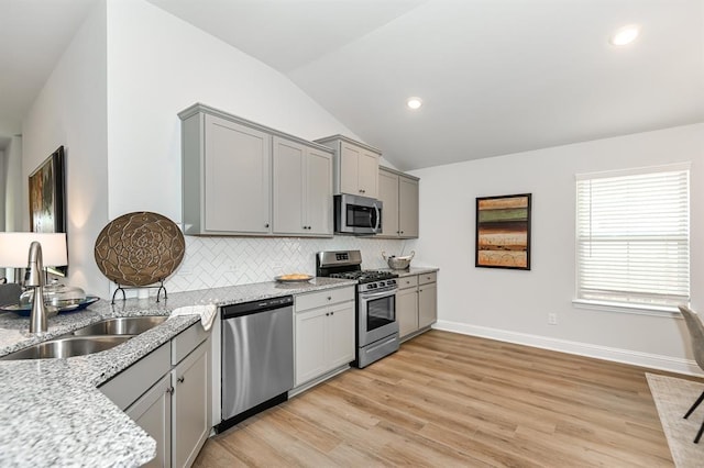 13620 Sorico Bay Dr, Texas City, TX 77568 - kitchen with stainless steel appliances, gray cabinetry, a sink, vaulted ceiling, and decorative backsplash