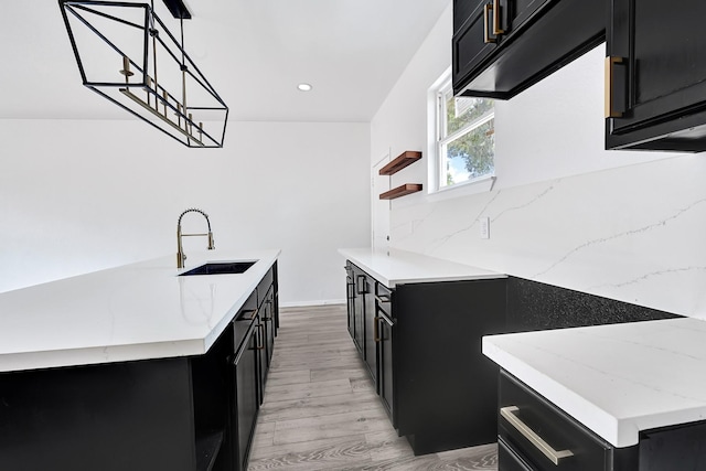 7939 Goode St, Houston, TX 77012 - kitchen with dark cabinetry, a sink, light wood finished floors, light stone countertops, and recessed lighting