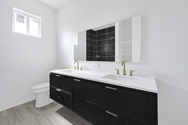 7939 Goode St, Houston, TX 77012 - bathroom featuring toilet, double vanity, wood finished floors, a tile shower, and baseboards