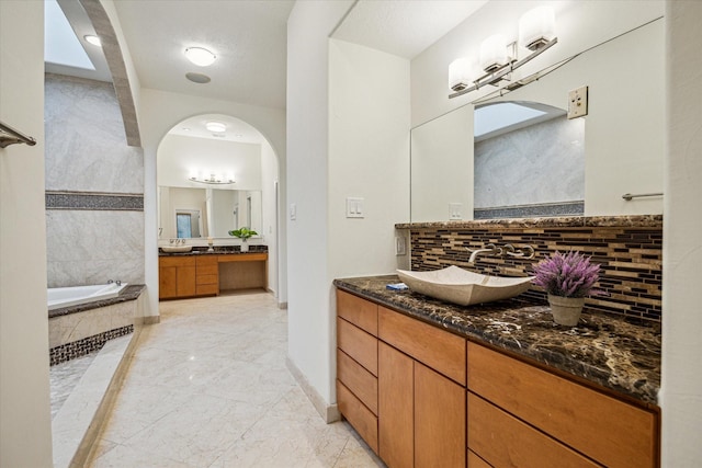 3224 Alabama Ct, Houston, TX 77027 - bathroom with marble tiled floors, a bath, two vanities, backsplash, and baseboards