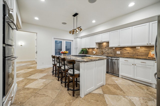 3224 Alabama Ct, Houston, TX 77027 - kitchen featuring stainless steel appliances, decorative backsplash, white cabinets, a kitchen island, and dark stone counters