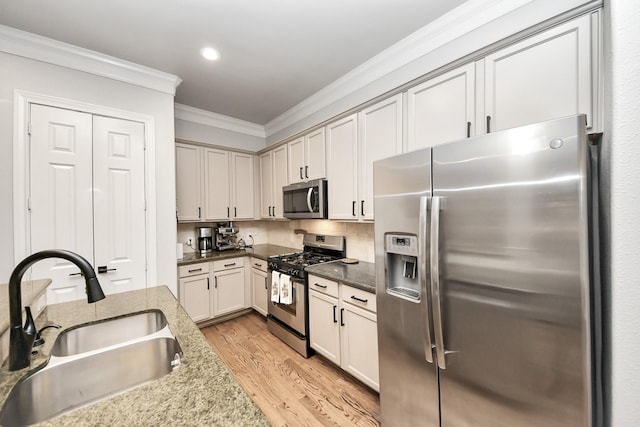 2223 Hilshire Trail Dr, Houston, TX 77080 - kitchen featuring appliances with stainless steel finishes, a sink, ornamental molding, light wood-style flooring, and dark stone counters