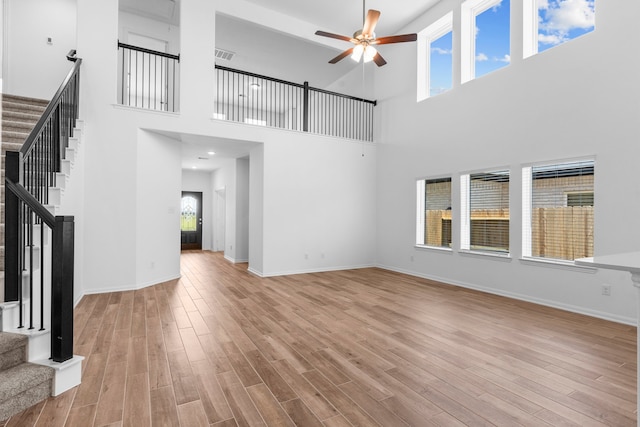 9022 Gull Cyn, Downs, Baytown, TX 77521 - unfurnished living room featuring stairway, ceiling fan, wood finished floors, baseboards, and a towering ceiling