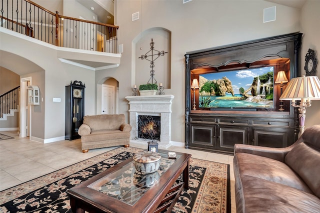 25606 Payton Chase Ct, Katy, TX 77494 - living room featuring arched walkways, a towering ceiling, light tile patterned floors, baseboards, and a lit fireplace