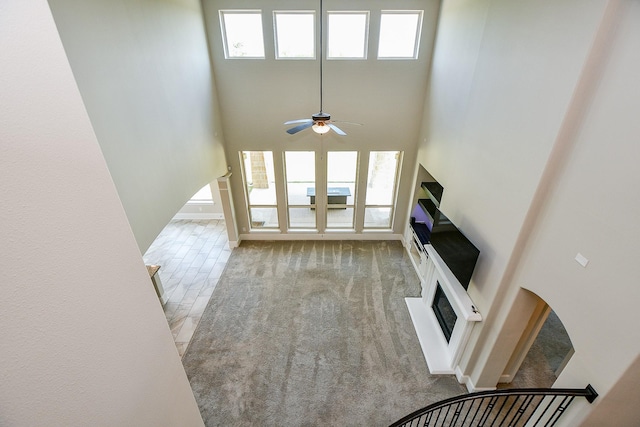 23402 Skylark Falls Trl, Katy, TX 77493 - unfurnished living room with a glass covered fireplace, ceiling fan, and a high ceiling