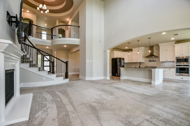 23402 Skylark Falls Trl, Katy, TX 77493 - unfurnished living room featuring a towering ceiling, recessed lighting, arched walkways, a chandelier, and light carpet
