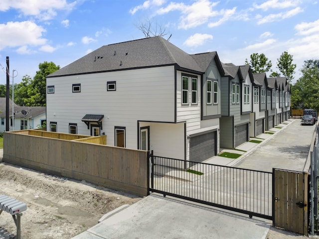 2410 Vaughn St Unit B, Houston, TX 77093 - view of property exterior with a gate, a garage, a shingled roof, concrete driveway, and a residential view