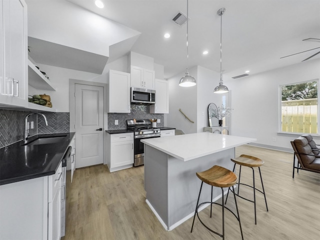2410 Vaughn St Unit B, Houston, TX 77093 - kitchen featuring appliances with stainless steel finishes, a sink, a breakfast bar area, open shelves, and white cabinetry