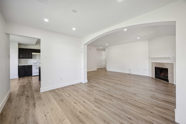 4615 Pleasant Trl, Fresno, TX 77545 - unfurnished living room featuring recessed lighting, light wood finished floors, a tiled fireplace, baseboards, and arched walkways