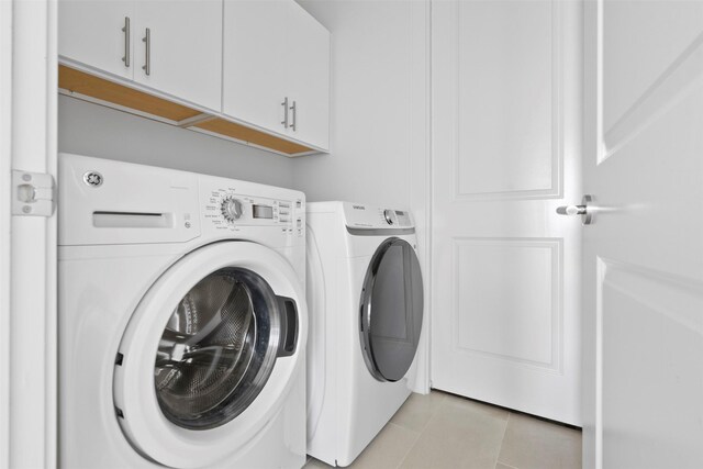 2047 Westcreek Ln Unit 1105, Houston, TX 77027 - washroom featuring cabinet space, washing machine and dryer, and light tile patterned floors