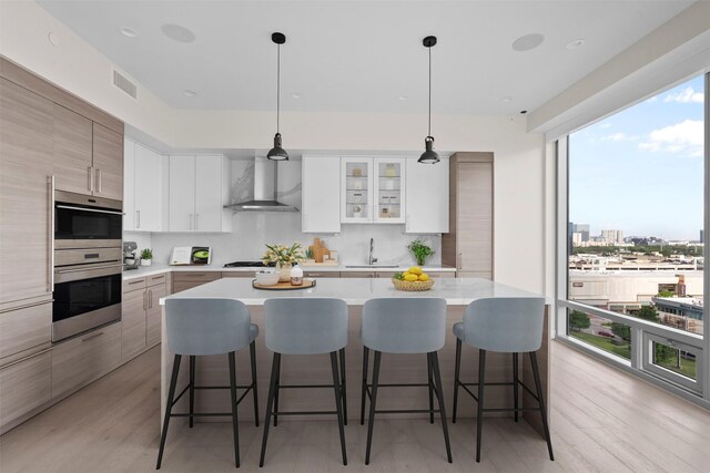 2047 Westcreek Ln Unit 1105, Houston, TX 77027 - kitchen with wall chimney exhaust hood, stainless steel double oven, a kitchen breakfast bar, and tasteful backsplash