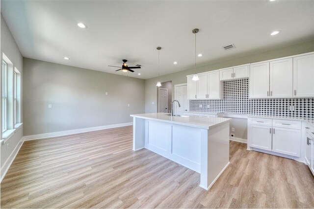 502 W Francis St, Baytown, TX 77520 - kitchen with a sink, a ceiling fan, decorative backsplash, light wood-style flooring, and white cabinetry