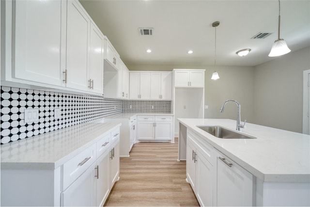 502 W Francis St, Baytown, TX 77520 - kitchen featuring a sink, tasteful backsplash, light wood-style flooring, a kitchen island with sink, and white cabinets