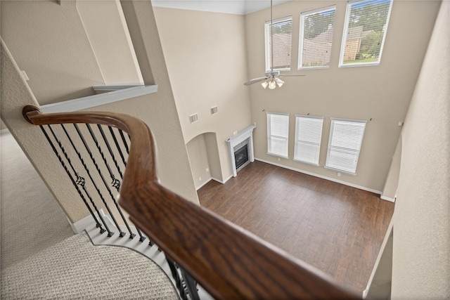 23918 Windsor Canyon Ct, Spring, TX 77389 - staircase with wood finished floors, a ceiling fan, baseboards, a glass covered fireplace, and a towering ceiling
