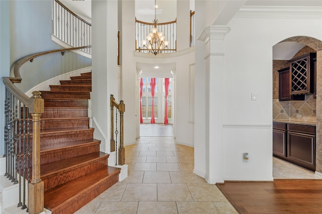 9431 Copper Cove Ln, Rosharon, TX 77583 - foyer featuring stairs, arched walkways, a chandelier, a high ceiling, and light tile patterned floors