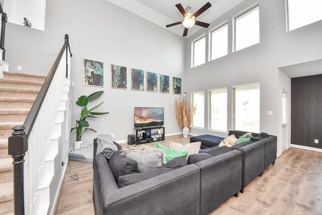 8219 Oxbow Manor Ln, Cypress, TX 77433 - living area featuring a ceiling fan, light wood-style flooring, a high ceiling, stairway, and baseboards