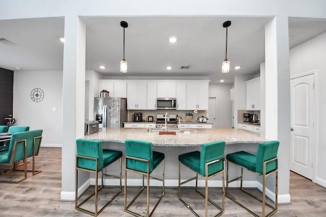 8219 Oxbow Manor Ln, Cypress, TX 77433 - kitchen featuring appliances with stainless steel finishes, white cabinetry, tasteful backsplash, light wood-style floors, and recessed lighting
