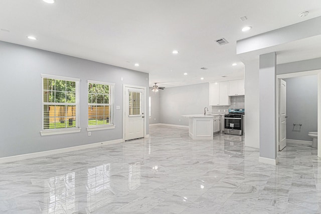 4801 Marquita Ln, Houston, TX 77039 - kitchen featuring stainless steel stove, open floor plan, light marble finish floors, a sink, and white cabinetry
