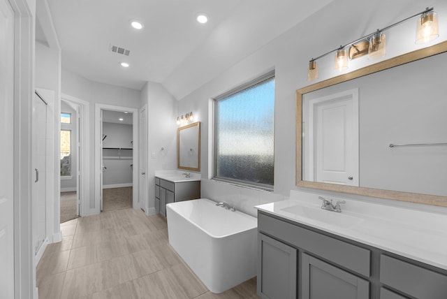21410 Flora Springs Ln, Magnolia, TX 77355 - bathroom featuring two vanities, a freestanding tub, a shower stall, recessed lighting, and baseboards