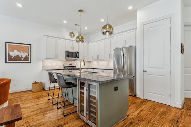 1250 Sampson St, Houston, TX 77003 - kitchen with stainless steel appliances, wine cooler, a center island with sink, wood finished floors, and recessed lighting