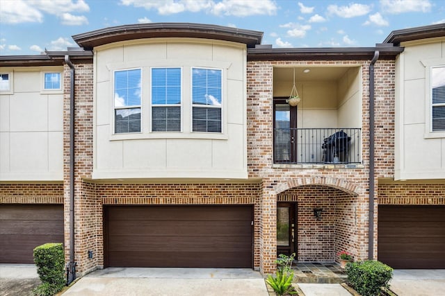 1250 Sampson St, Houston, TX 77003 - view of property featuring an attached garage, concrete driveway, a balcony, brick siding, and stucco siding