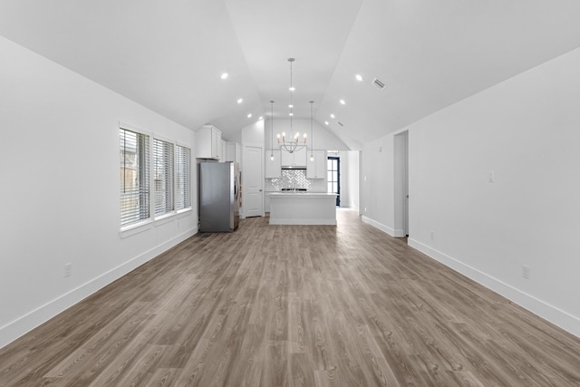 21318 Oakley Claremont Ct, Magnolia, TX 77355 - unfurnished living room with a chandelier, vaulted ceiling, baseboards, and wood finished floors