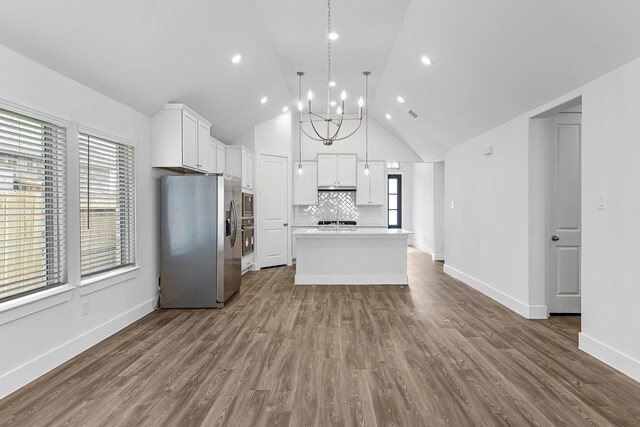21318 Oakley Claremont Ct, Magnolia, TX 77355 - kitchen featuring appliances with stainless steel finishes, a center island with sink, tasteful backsplash, light countertops, and dark wood-style flooring