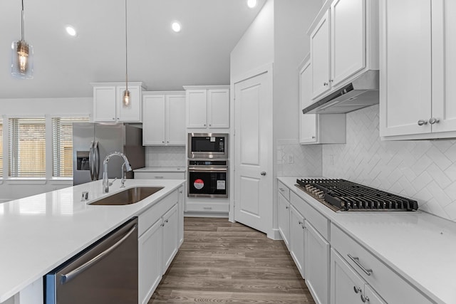 21318 Oakley Claremont Ct, Magnolia, TX 77355 - kitchen with appliances with stainless steel finishes, a sink, under cabinet range hood, light countertops, and vaulted ceiling