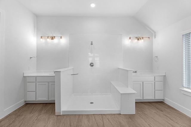 21318 Oakley Claremont Ct, Magnolia, TX 77355 - bathroom featuring two vanities, a tile shower, lofted ceiling, and baseboards