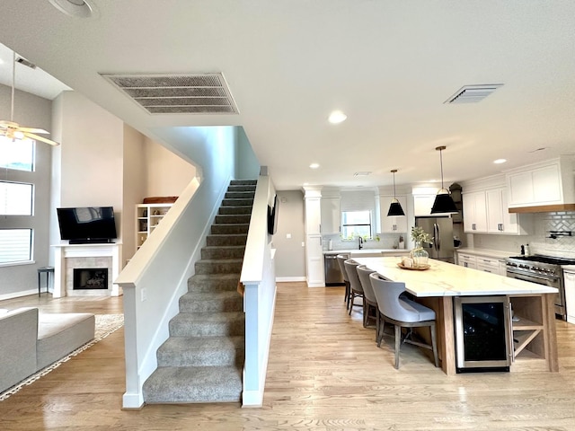5018 Darling St, Houston, TX 77007 - kitchen featuring appliances with stainless steel finishes, wine cooler, white cabinets, light wood-type flooring, and recessed lighting