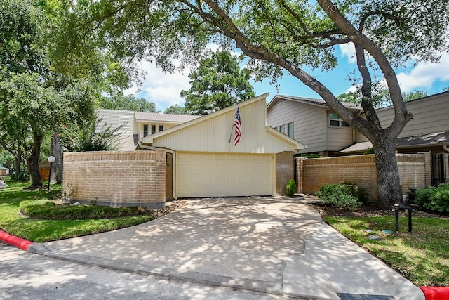8028 Oakwood Forest Dr, Houston, TX 77040 - mid-century modern home featuring a garage, concrete driveway, and brick siding