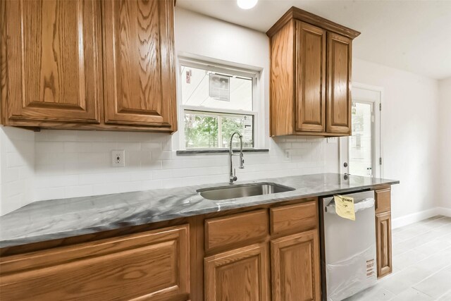 9096 N Comanche Cir, Willis, TX 77378 - kitchen featuring stainless steel dishwasher, a sink, brown cabinets, and tasteful backsplash