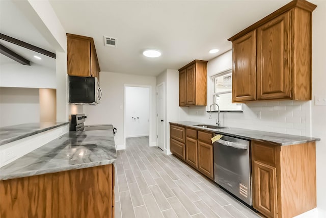 9096 N Comanche Cir, Willis, TX 77378 - kitchen with appliances with stainless steel finishes, a sink, baseboards, brown cabinetry, and decorative backsplash
