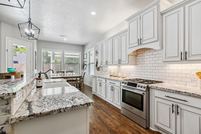 1935 Invermere Dr, Spring, TX 77386 - kitchen with stainless steel gas range oven, backsplash, dark wood-style floors, an island with sink, and light stone countertops
