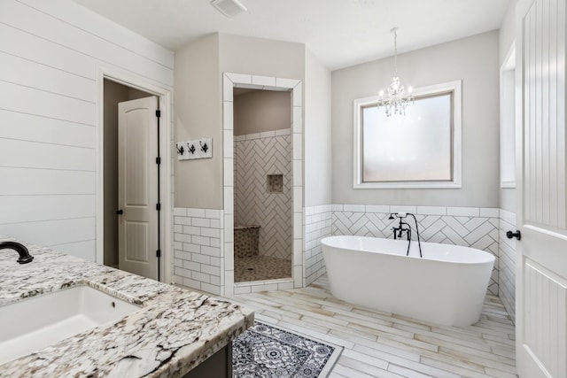1935 Invermere Dr, Spring, TX 77386 - full bath with a tile shower, a freestanding tub, vanity, a chandelier, and tile walls