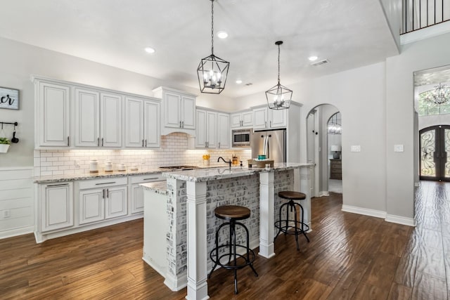 1935 Invermere Dr, Spring, TX 77386 - kitchen with stainless steel appliances, arched walkways, dark wood finished floors, decorative backsplash, and recessed lighting