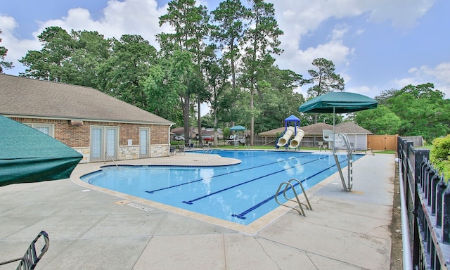 1935 Invermere Dr, Spring, TX 77386 - community pool featuring a patio area, a water slide, and view of wooded area